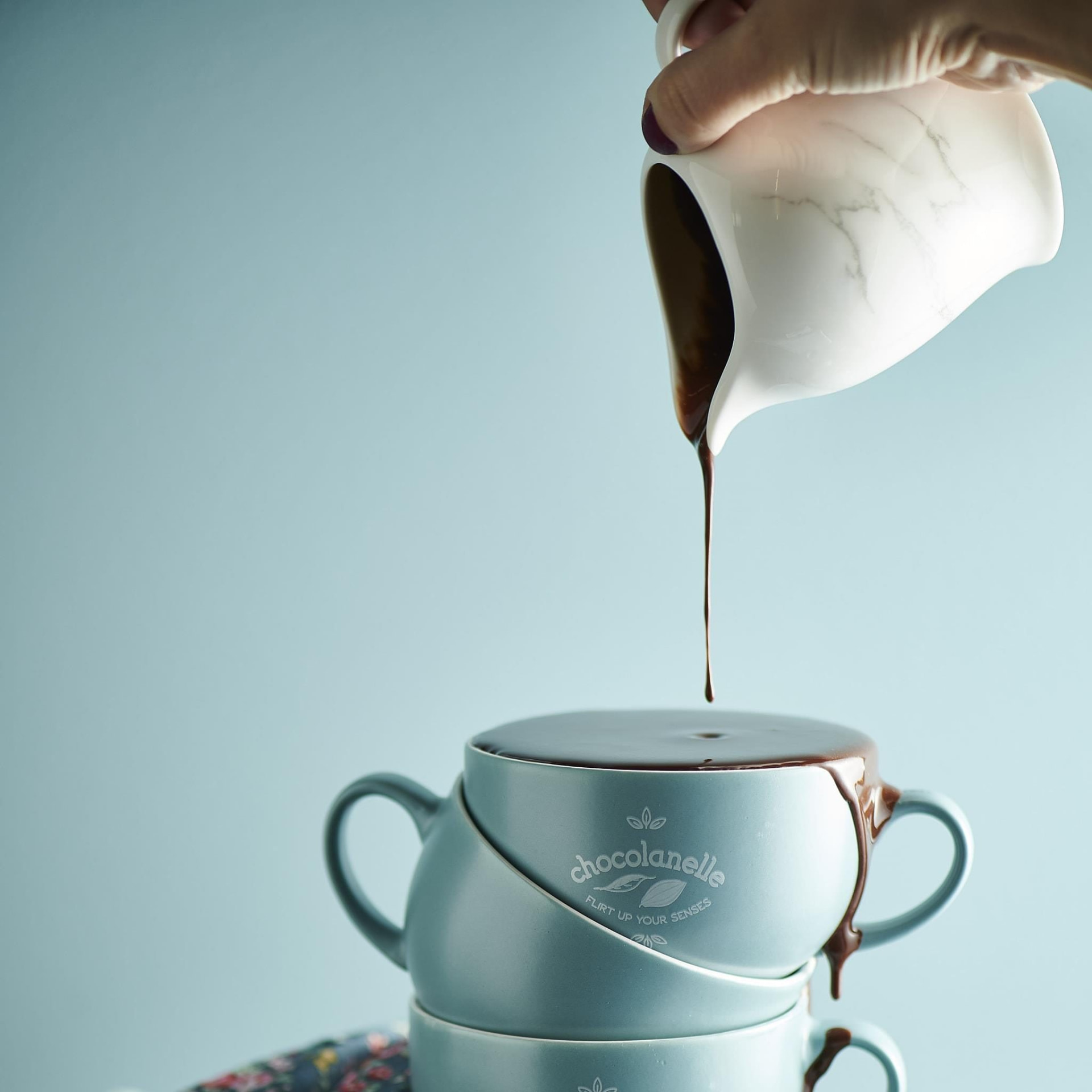 Warme chocolade wordt uit een kannetje in een gestapelde Chocolanelle-kop gegoten