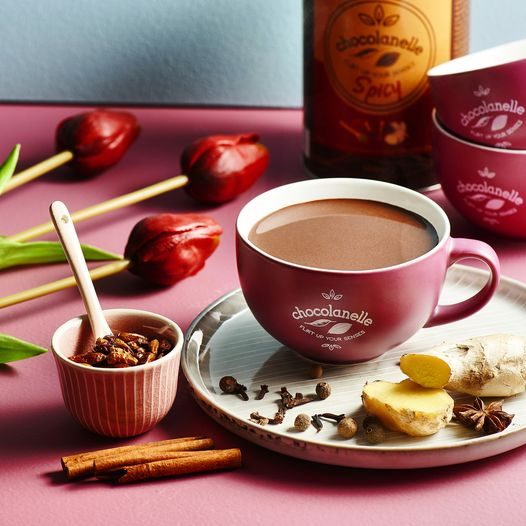 Chocolanelle Spicy in een roze kop met kaneel, kruidnagel en gember ernaast